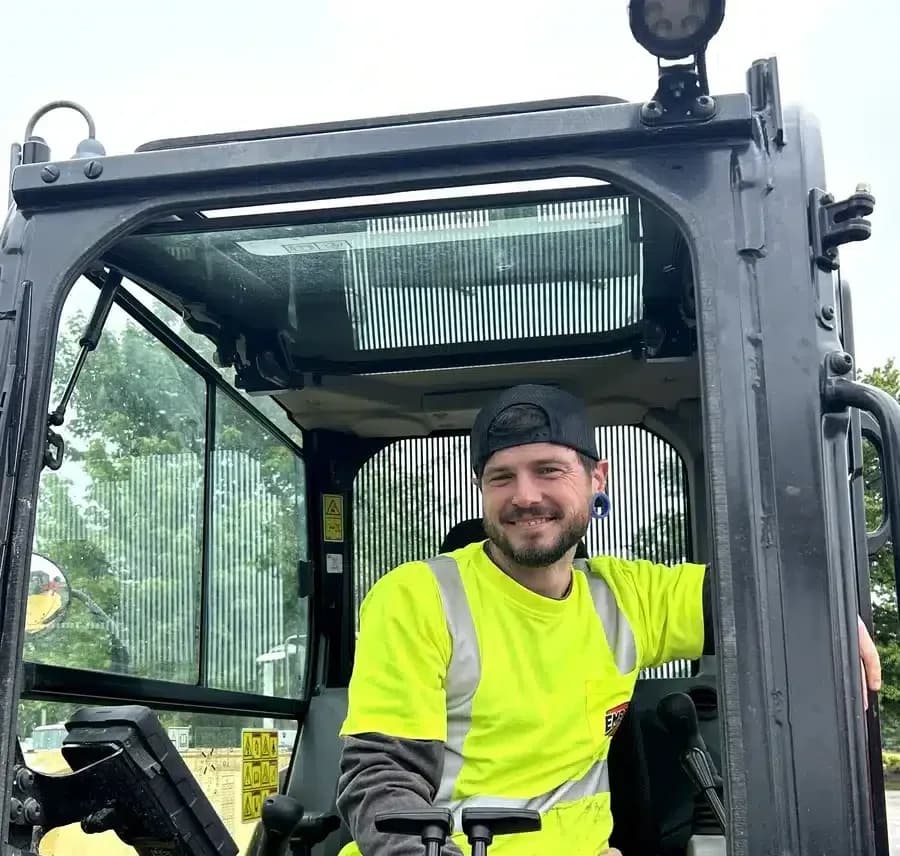 Embrich Plumbing, Heating & Air Conditioning employee posing inside excavator at Touch-A-Truck event