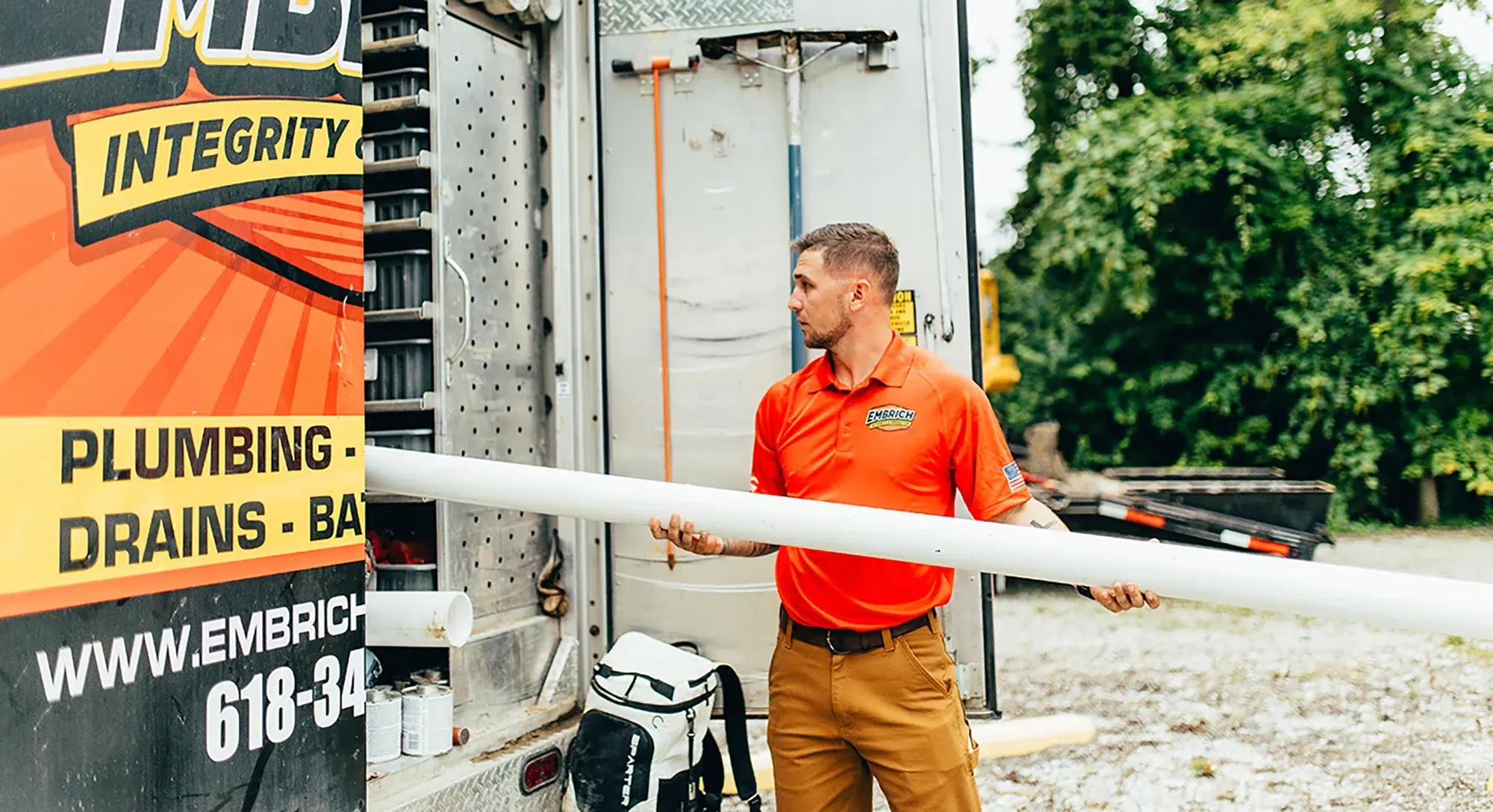 Embrich Plumbing, Heating & Air Conditioning service expert inspecting pipe outdoors during a plumbing service call in Collinsville