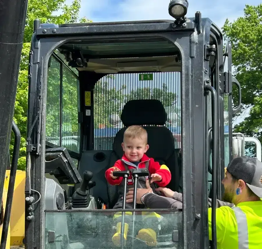 Child smiling inside excavator during Embrich Plumbing, Heating & Air Conditioning Touch-A-Truck event