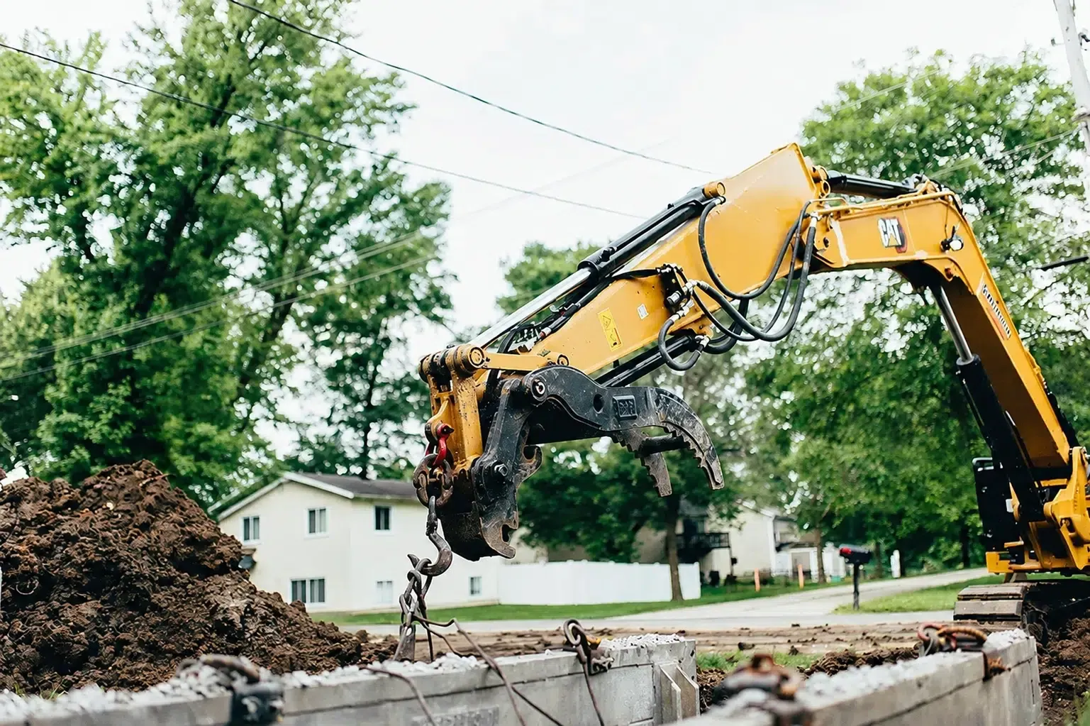 Excavator at a residential excavation site for sewer line replacement by Embrich Plumbing.