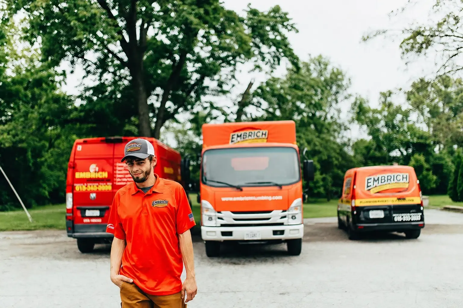 Embrich Plumbing, Heating & Air technician standing in front of branded service vans