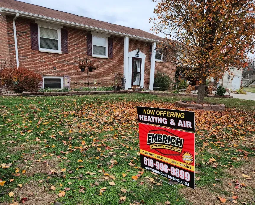 Embrich Plumbing, Heating & Air yard sign advertising HVAC and plumbing services outside a brick home.