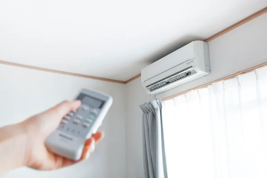 Wall-mounted ductless mini-split air conditioner controlled by a handheld remote