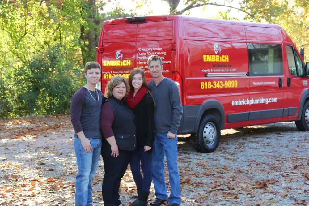 Embrich Plumbing, Heating & Air Conditioning team posing together in front of branded service van