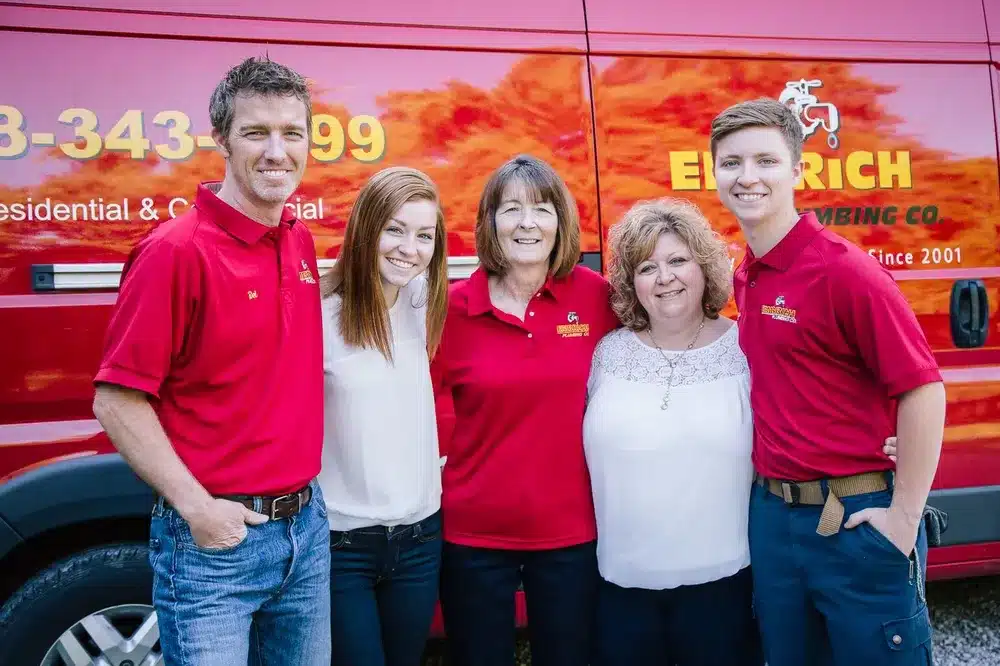 Embrich Plumbing, Heating & Air Conditioning team members smiling together in front of branded service truck