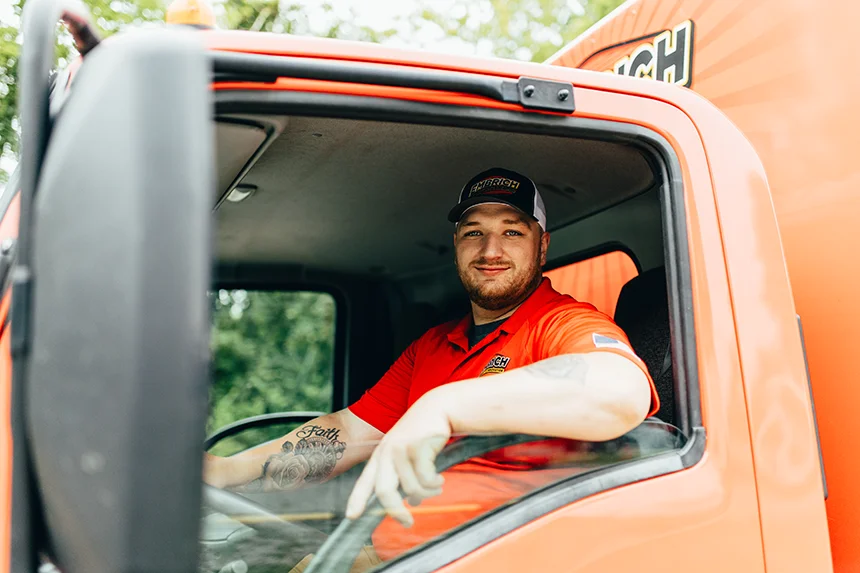 Embrich Plumbing, Heating & Air Conditioning service expert sitting in orange branded service truck ready for a plumbing job in Collinsville