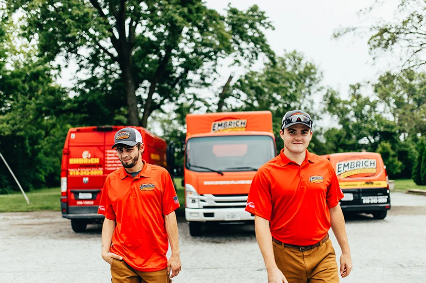 Embrich Plumbing, Heating & Air Conditioning service expert walking past branded plumbing service truck in Collinsville