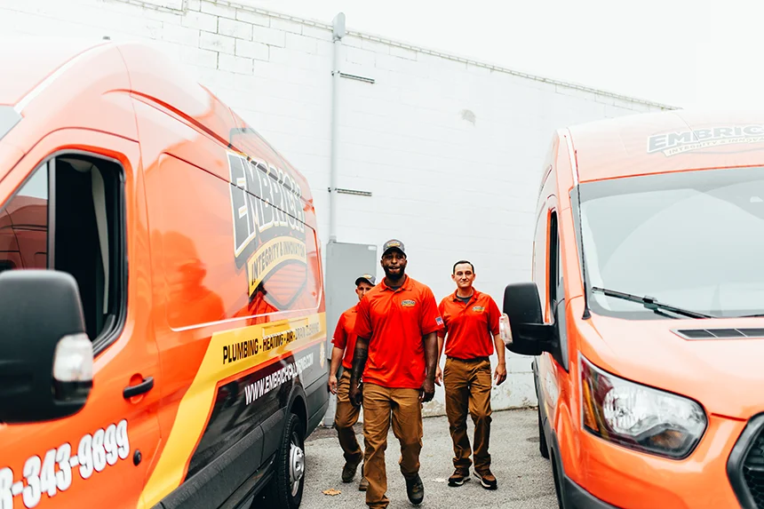Embrich Plumbing, Heating & Air Conditioning team members walking alongside branded plumbing service van in Collinsville