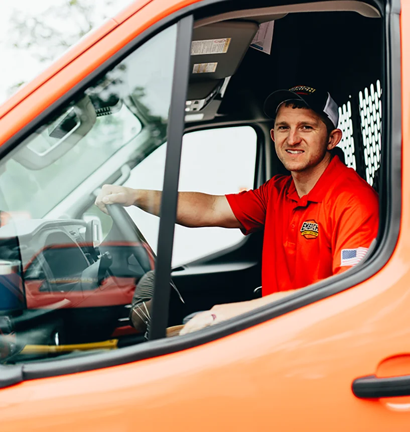 Embrich Plumbing, Heating & Air Conditioning service expert smiling while driving company service van in Collinsville