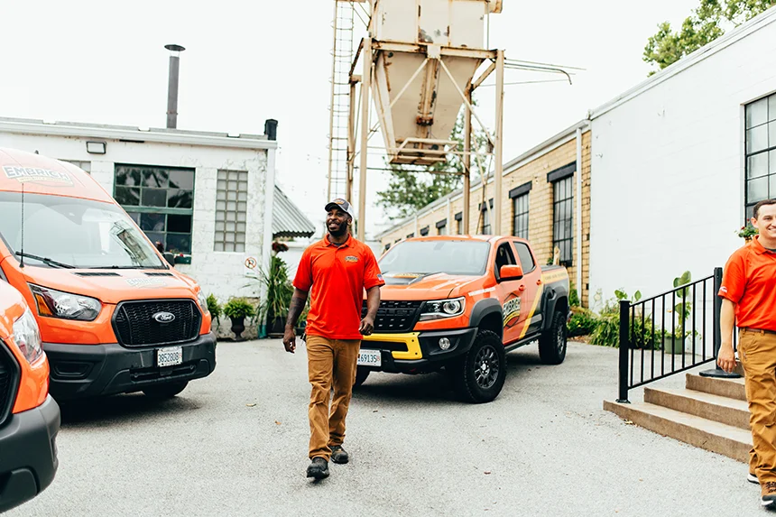 Embrich Plumbing, Heating & Air Conditioning service expert walking between service trucks at job site in Collinsville