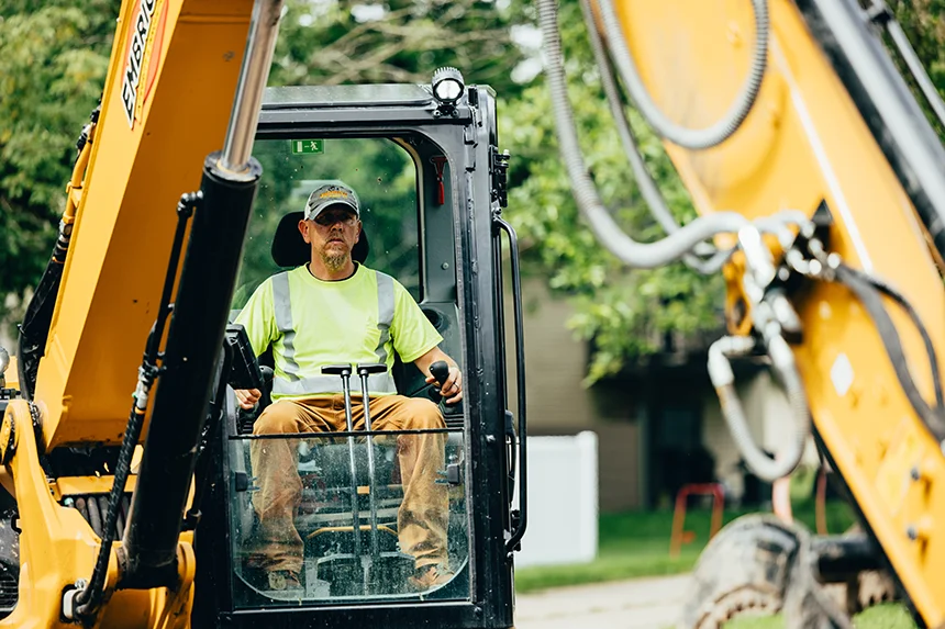 Embrich Plumbing, Heating & Air Conditioning service expert operating excavator during plumbing excavation project in Collinsville