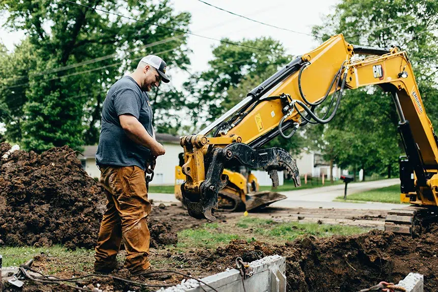 Embrich Plumbing, Heating & Air Conditioning service expert operating excavator during sewer or water line repair in Collinsville