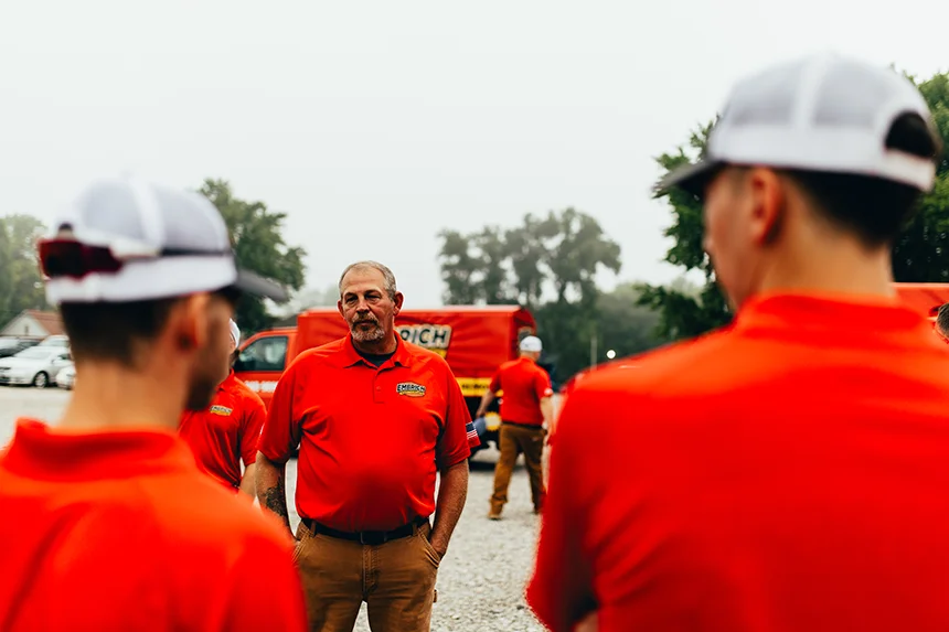 Embrich Plumbing, Heating & Air Conditioning team members discussing a plumbing project outdoors on a job site in Collinsville