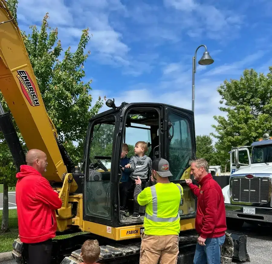 Embrich Plumbing team members helping children explore construction equipment at Touch-A-Truck event