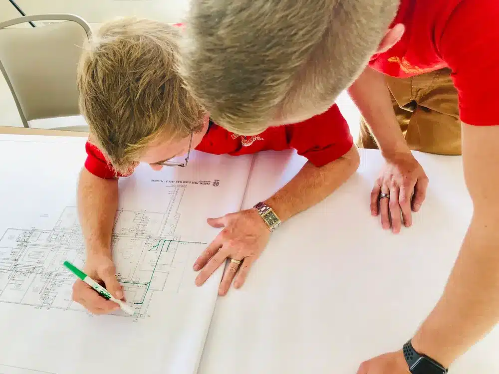Embrich Plumbing, Heating & Air Conditioning technician measuring and planning project layout on large sheet
