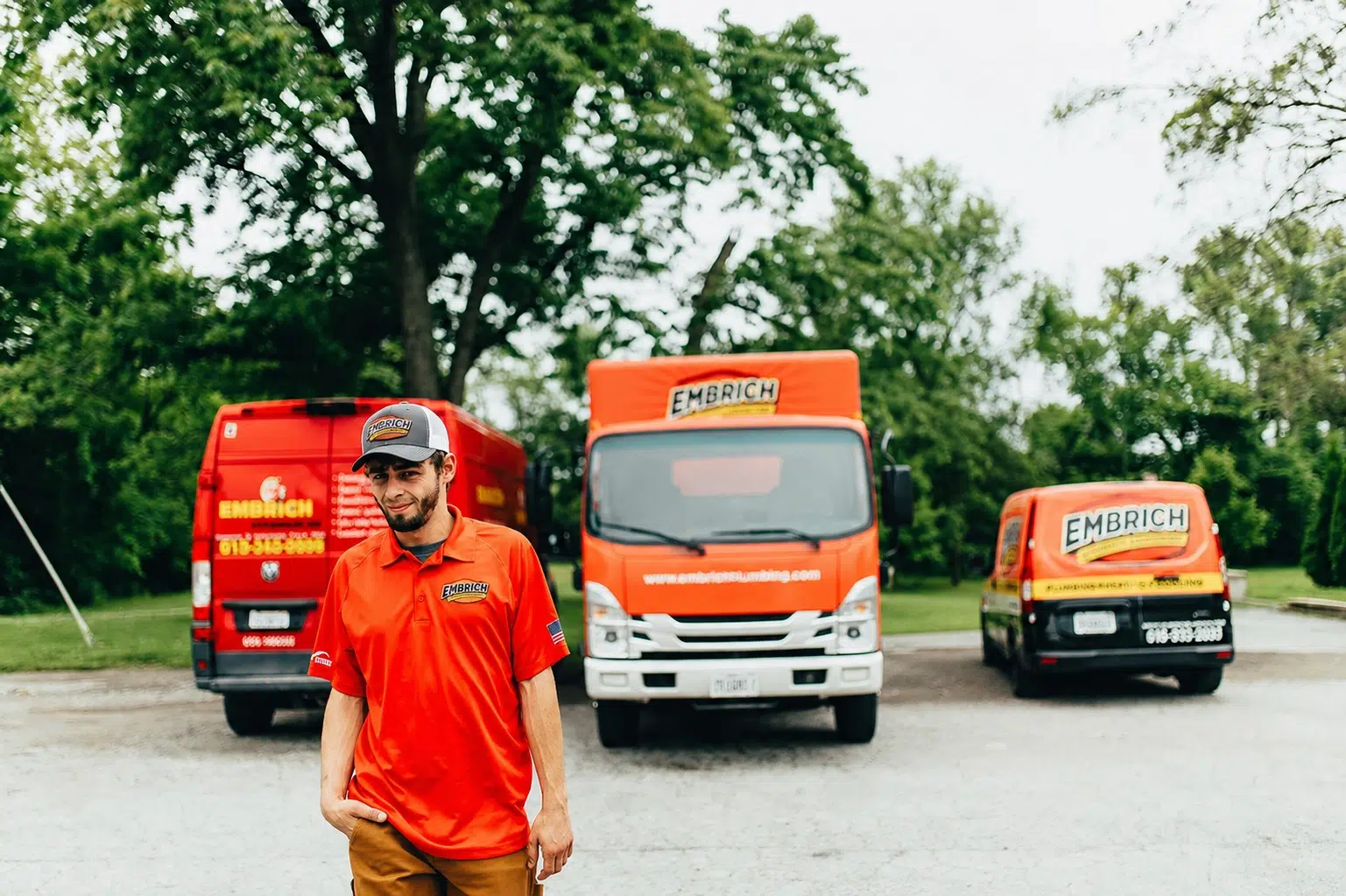 Embrich Plumbing, Heating & Air technician standing in front of branded service vans