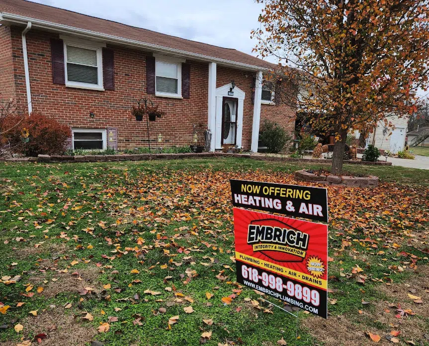 Embrich Plumbing, Heating & Air yard sign advertising HVAC and plumbing services outside a brick home.