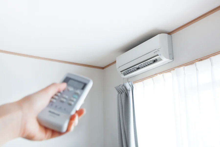 Wall-mounted ductless mini-split air conditioner controlled by a handheld remote